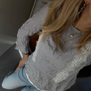 Randig blus med volangdetalj - Säljer en snygg blus med smala svarta och vita ränder. Blusen har lång ärm, rund halsringning och volangdetalj nedtill. Materialet känns lätt och luftigt, perfekt för vår och sommar. Passar till både jeans och kjol för en chill look.