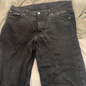 Svarta jeans från Sweet Skateboarding - Svarta jeans från Sweet Skateboarding med broderad logga vid fickan och klassisk läderpatch bak. Jeansen har raka ben och normal passform, tillverkade i slitstarkt bomullstyg. Perfekta för dig som gillar streetwear och skate.