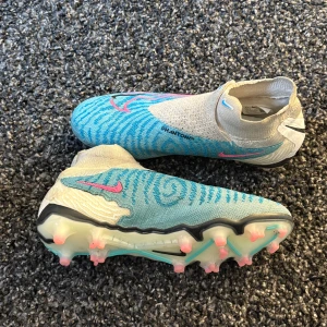 Nike Phantom GX Elite fotbollsskor blå/vit - Nike Phantom GX Elite fotbollsskor i blått och vitt med rosa detaljer och svart sula. Skorna är i |8/10| skick och är sjukt snygga skynda dig dessa blir sålda fort 