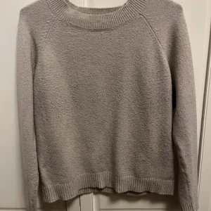 Beige stickad tröja från Vero Moda - Mysig beige stickad tröja från Vero Moda med rund halsringning och ribbade muddar vid ärmslut och nederkant. Perfekt för lager-på-lager och enkel att matcha med jeans eller kjol. Klassisk och stilren modell som funkar året runt.