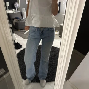 Ljusblå raka jeans med låg midja - Säljer ett par ljusblå jeans med låg midja och raka ben. Jeansen har klassisk femficksdesign och stängs med knapp och dragkedja. Perfekta för en avslappnad och trendig look. Materialet är jeans i bomull.