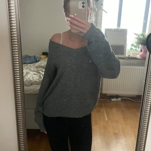Grå offshoulder stickad tröja - Mysig grå stickad tröja med offshoulder-design och lång ärm. Tröjan har en loose passform och är perfekt för dig som gillar en avslappnad och trendig stil! Stor i storlek och den har blivit lite nopprig.