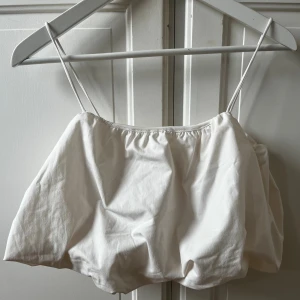 Vit croppad linnetopp från H&M - Säljer en vit croppad linnetopp från H&M med tunna axelband och lätt puffig form. Toppen är ärmlös och har en enkel, stilren design som passar perfekt till varma dagar. Materialet är mjukt och känns skönt mot huden. Ny aldrig använt 