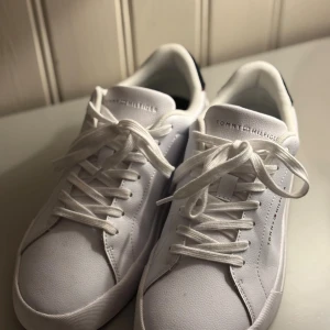 Vita sneakers Tommy Hilfiger - Fräscha vita sneakers från Tommy Hilfiger. Skorna har snygga snörningar och subtilt logotyptryck på sidan och plösen. Skorna är endast använda vid ett tillfälle tidigare. 