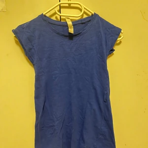 Blå kortärmad klänning från Crossbow - Enkel blå kortklänning från Crossbow i mjuk bomull. Modellen är rak med rund halsringning och korta ärmar. Perfekt för en avslappnad look och lätt att matcha med sneakers eller sandaler.