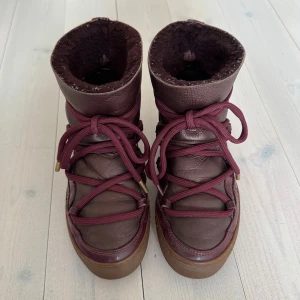 Inuikii vinterskor  - Använda, men fortfarande i gott skick. Små sprickor i lacken finns på vissa ställen, men är inte mycket synliga vid användning. (En metall detalj är borta på ena snöret.) Lila/brun/röd färg. Kolla in min profil för fler inuikii vinterskor.🙌