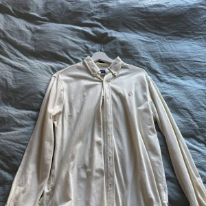 Klassisk beige skjorta från Polo Ralph Lauren - Snygg beige skjorta från Polo Ralph Lauren med button-down krage och broderad logga på bröstet. Skjortan har lång ärm, knappar framtill och är gjord i mjuk bomull. Använd endast några gånger i somras 9/10 skick. Nypris 1799kr 