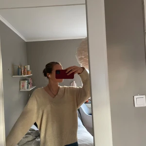 Beige stickad tröja  - Superfina stickad tröja som är köpt i Barcelona. Jättefin V-ringning och en fin beige färg. Den har en liten fläck (se bild) men förutom det så är den i väldigt fint skick och inte så använd. Hör av er vid frågor eller funderingar och kolla gärna in min profil för andra snygga plagg! 