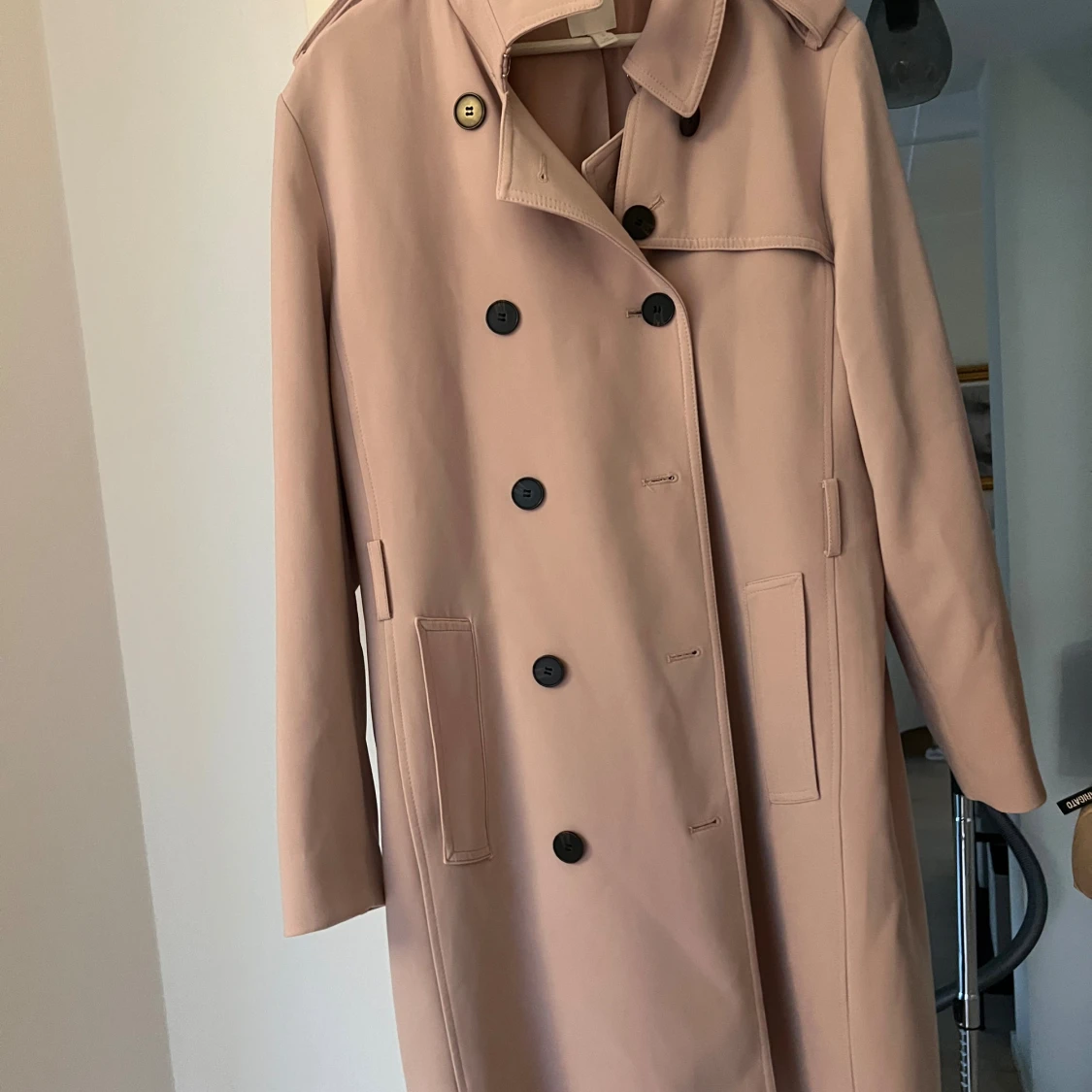 Ljusrosa trenchcoat med svarta knappar