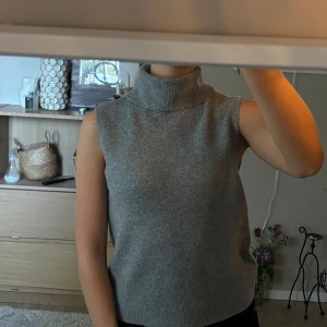 Grå ärmlös polotopp - Helt ny, oanvänd grå stickad polo tröja utan ärmar. Mjuk, bekväm och elegant. Säljs ej längre Orginalpris: 159kr Storlek S