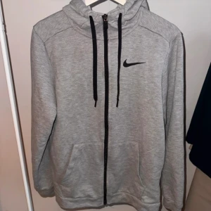 Grå hoodie från Nike - Grå herrtröja med luva från Nike i storlek S. Har lite noppor (se bild) men är annars hel och ren.