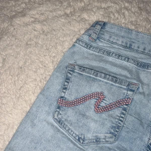 Low waist bootcut nelly jeans rosa - low waist bootcut jeans från Nelly med Rosa mönster på fickorna där bak och hål för knäna