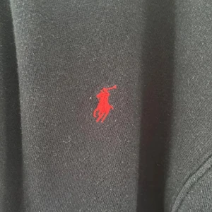 Marinblå hoodie från Polo Ralph Lauren - Marinblå hoodie från Polo Ralph Lauren i storlek 18-20 med klassisk röd broderad logga på bröstet. Tröjan har huva och dragkedja framtill, samt långa ärmar. Perfekt för en avslappnad och stilren look. Pris kan diskuteras vid snabb affär.