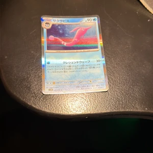サクラビス (Sakurabisu) - Upptäck en japansk Pokémon-kort med holografisk finish! Perfekt för samlare och fans av Pokémon. Kortet visar en färgstark och unik Pokémon, och är ett måste för dig som älskar spel, samlingar och coola kort. Skapa din egen Pokémon-upplevelse med detta exklusiva kort!