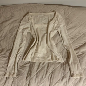 Beige långärmad topp med fyrkantig hals - Säljer en beige långärmad topp med snygg fyrkantig halsringning. Modellen är slim och har en enkel, stilren design utan mönster eller detaljer. Materialet känns mjukt och lätt, perfekt för dig som gillar minimalistiska plagg med clean vibe.