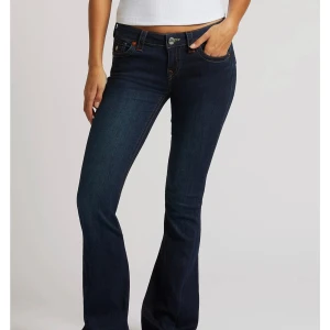 Mörkblå bootcut true religon jeans - Snygga mörkblå jeans från Levis med klassisk bootcut-passform och låg midja. Jeansen har fem fickor, orangea sömmar och är tillverkade i stretchig denim som sitter skönt. Perfekta för dig som gillar en tidlös och trendig look. Lite skavanker längst ner men syns ej när man har på sig dom