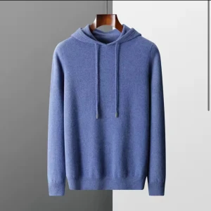 Blå stickad hoodie i merinoull  - Mysig blå stickad hoodie med huva och långa ärmar. Tröjan har ribbade muddar och snörning i halsen för en avslappnad look. Perfekt för dig som gillar stilren och enkel design.