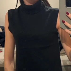 Svart polotopp från Zara, S - Svart polotopp från Zara i storlek S. Toppen är ärmlös med hög, ribbad polokrage och har en clean, rak passform. Materialet är mjukt och stickat, vilket gör den både bekväm och snygg. Perfekt att styla med jeans eller kjol för en cool look. Använd jättefå gånger tror max 1 gång och kommer lägst för 75