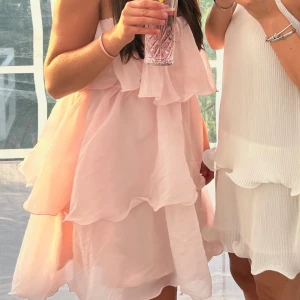 Ljusrosa volangklänning offshoulder - Superfin ljusrosa kortklänning med flera lager volanger och offshoulder-modell. Klänningen har en luftig och flowy känsla, perfekt för varma dagar. Materialet är tunt och ger en romantisk vibe. Säljer då den inte längre kommer till användning.