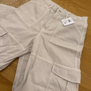 Beiga byxor från Carin Wester - Stilrena cargopants från Carin Wester i en superfin beige färg. Byxorna har flera fickor fram på benen och bak, samt bälteshällor och klassisk knappstängning. Perfekta för en avslappnad och trendig look. Oanvända med prislapp kvar! Nypris 800kr🩷
