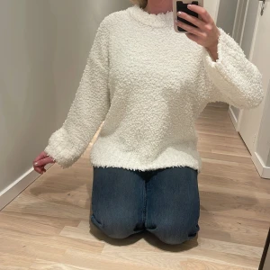 Vit fluffig tröja från Divided - Supermjuk och fluffig vit tröja från Divided i storlek S. Tröjan har långärmade ärmar och en rund halsringning. Materialet är syntetiskt och har en mysig teddystruktur som gör den extra skön att bära. Perfekt för kyliga dagar när du vill vara både bekväm och snygg.