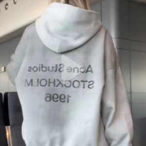 Grå hoodie Acne Studios Stockholm - Säljer en grå hoodie från Acne Studios med tryck på ryggen: 'Acne Studios STOCKHOLM 1996'. Tröjan har huva, ribbade muddar och en loose passform. Perfekt för dig som gillar stilren streetwear med svensk design.