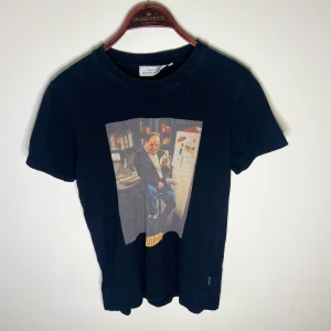 Svart Seinfeld t-shirt från Dedicated - Svart t-shirt från Dedicated med ikoniskt Seinfeld-tryck framtill. Gjord i ekologisk bomull och har en riktigt nice slimmad fit tröjan är defekt fri, frågor/funderingar hör av dig 🤙🏽 