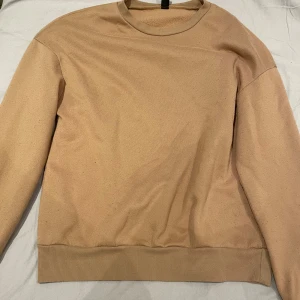 Beige sweatshirt med rund hals - En enkel och stilren beige sweatshirt med rund hals och ribbade muddar vid ärmslut och nederkant. Tröjan har lång ärm, perfekt för chill dagar och sköna outfits.