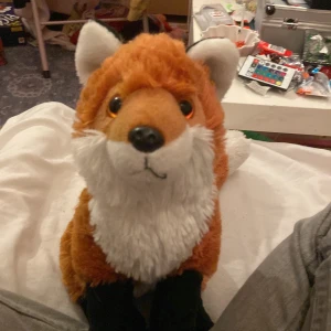 Mjukisdjur räv - Söt och mjuk räv i plysch med orange päls, vit svansspets och svart ben. Perfekt som present eller dekoration. Ser ut att vara i mycket gott skick utan synligt slitage eller defekter. Passar både barn och vuxna som gillar djur.