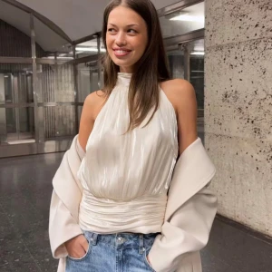 Champagnefärgad omlott polotopp - Säljer en champagnefärgad Fest till. Toppen är ärmlös och har ett glansigt, skirt material som ger en lyxig känsla. Passformen är loose och toppen har en bred, draperad midja. Använd 3 gånger på ute kväll. Nypris 350kr och köparen står för frakt.