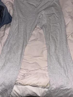 Gråa mjuka loungebyxor - Ett par gråa loungebyxor i mjukt och stretchigt material, perfekta för att chilla hemma. Byxorna har rak passform och resår i midjan för extra komfort. Passar dig som vill ha något enkelt och bekvämt att slappa i.