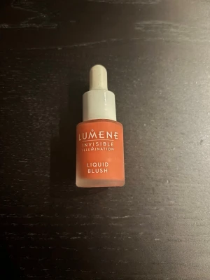 Lumene Invisible Illumination Liquid Blush - Flytande rouge från Lumene i en fräsch persikorosa nyans. Kommer i en liten glasflaska med pipett för enkel applicering. Perfekt för att ge kinderna en naturlig glow och fräsch färg. Snygg minimalistisk design med frostat glas och vit kork.