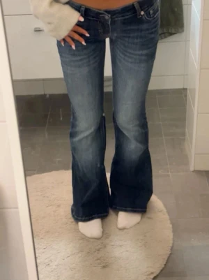 Lågmidjade bootcut jeans lager 157 - Snygga mörkblå bootcut jeans från Levi's med klassisk femficksdesign och låg midja. Jeansen har en lätt tvättad look och är tillverkade i slitstark bomullsdenim. Perfekta för dig som gillar en retroinspirerad stil med utsvängda ben. Short längd. Passar någon som är mellan 160-168 uppskattar jag 