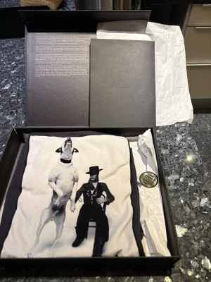 Svart t-shirt från Limitato -  svart t-shirt från Limitato med ett stort svartvitt tryck framtill som föreställer en hund och en person i kostym och hatt. T-shirten har rund hals och korta ärmar. Perfekt för dig som vill sticka ut med en unik design. Skriv vid fundering 