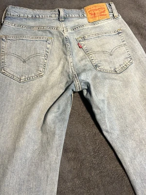 Levi's 514 ljusblå raka jeans - Klassiska ljusblå Levi's 514 jeans med raka ben och femficksmodell. Jeansen har den ikoniska läderpatchen bak i midjan och röd Levi's-tagg på bakfickan. Tillverkade i slitstark bomullsdenim, perfekt för en avslappnad och tidlös look.      W29 L30