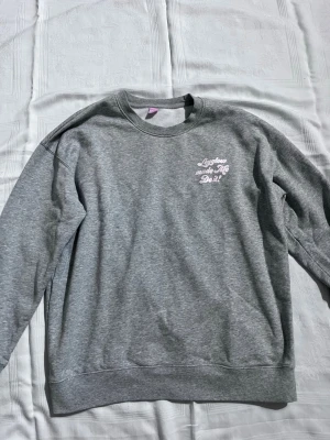 Grå sweatshirt från GLOWiD - Grå sweatshirt med tryck fram 'Lexglow made me do it!' och bak 'Get, Set, Glow!'. Skön och avslappnad passform, rund hals och långa ärmar. Perfekt för chill dagar eller när du vill ha en enkel men snygg look.