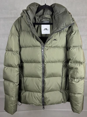 J.Lindberg Vinterjacka Pufferjacket - J.Lindeberg vinterjacka | Färg: Grön | Storlek: M | Skick: Mycket bra, lite små fläckar. Går kanske bort i tvätt har ej testat. | Hör av dig vid frågor och funderingar! 