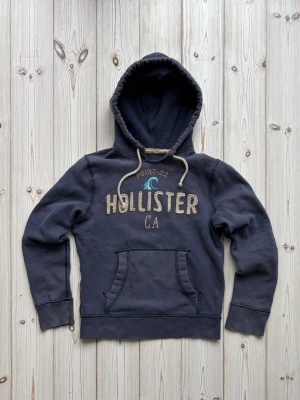 Hollister hoodie - Säljer nu denna riktigt snygga vintage Hollister hoodien. Finns ett väldigt litet hål på baksidan av hoodien som knappast är synlig. Slitningarna på texten är en del av vintage looken. Storlek: S. Pris: 649kr. Skriv vid frågor eller för mer bilder! 🤩
