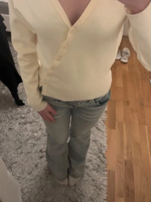 Gina tröja  - Säljer en ribbad kofta med djup v-ringning och knappar framtill från Gina tricot. Aldrig använd🩷ljusgul/ beige färg 