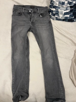 Grå  jeans från Nudie Jeans - Ett par grå och vackra Nudie jeans. Knappt använda då de varit lite små för mig så de är i mycket bra skick!