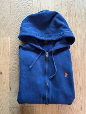 Polo Ralph Lauren zip hoodie -  Väldigt schysst Ralph Lauren Zip hoodie i mörkare blå med röd logga. Storleken är en junior medium eller vuxen small. Den passar bra för individer som är ca 175 cm.