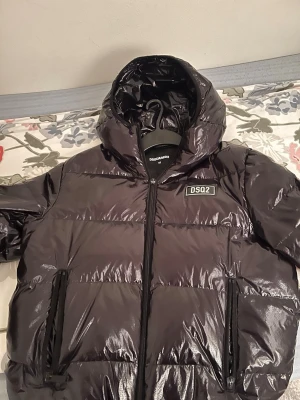 DSQUARED2 dunjacka - Hej säljer min DSQ2 jacka som bara tar plats i förrådet då den ej används längre. Jackan är köpt i klädbutiken Joel i Borås. Modellen är en vadderad jacka i märket Dsquared2 i färgen Svart. Fin jacka i högglansig finish med loggan på  bröstet. Storlek 50 har för mig det är L eller M. Köpte den under 2024 eller sent 2023 för 8500 ligger runt ca 9-10. Finns tyvärr små defekter med dragkedjan som det synns annars inga slitage på själva jackan än dragkedjan. 