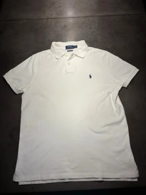 Ralph Lauren Pike - Säljer en riktigt klassisk, snygg Vit Pike från Ralph Lauren. Den är helt ny i skick. Storlek: L. Skriv vid frågor, öppen för bud!