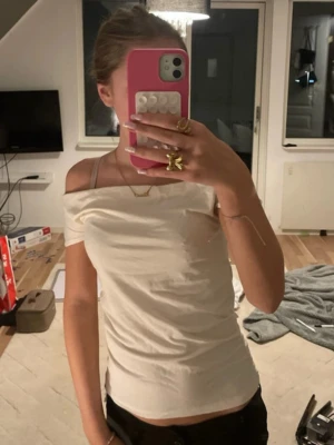Offshoulder vit topp - Säljer en stilren offshoulder topp i vit färg. T-shirten är ärmlös. Materialet känns mjukt och stretchigt, perfekt till sommaren. Passar dig som gillar enkel men snygg stil.