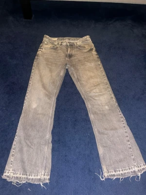 Grå bootcut jeans med rå kant - Säljer ett par gråa jeans med bootcut passform och råa, fransiga benslut. Jeansen har klassisk femficksdesign och är tillverkade i ett slitstarkt denimtyg. Hör av dig om du vill se hur de ser ut på! 
