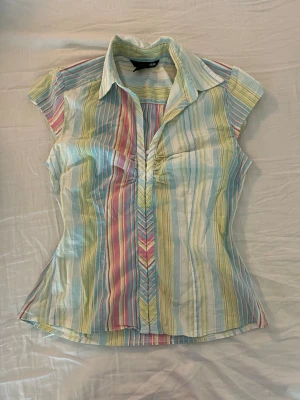 Somrig skjorta/korsett  - Säljer en super snygg kortärmad korsett/skjorta från H&M i storlek 38. Markerad midja och stängs med hakar framtill. Perfekt för vår och sommar! Stretchig tunt material💗