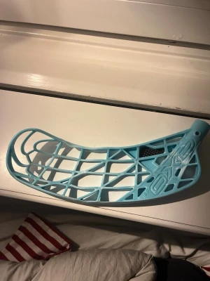 Blå innebandyblad från Oxdog - Säljer ett ljusblått innebandyblad från Oxdog med öppen konstruktion och tydliga ribbor. Bladet har en lätt böj och är tillverkat i slitstark plast. Perfekt för dig som vill byta blad på din klubba och få bättre bollkontroll.