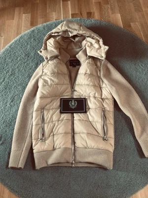Beige quiltad jacka med huva - ”Beige” cardigan jacka från Leon Marcel.     Endast använd 2 gånger, nypris: 1349kr, mitt pris: 900kr         OBS: DEN ÄR LITE MER BRUN ÄN PÅ BILDERNA