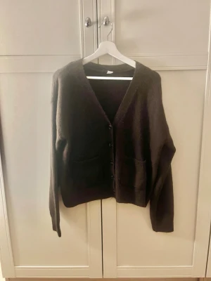 Mörkbrun oversized kofta - Mysig mörkbrun kofta med v-ringning och knäppning framtill. Modellen är oversized med långa ärmar och två stora fickor framtill. Perfekt att slänga på sig över en t-shirt eller topp för en avslappnad look. Och den är från H&M 