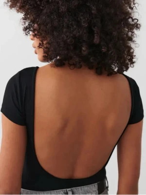 Svart topp med öppen rygg - Säljer en svart, tight topp med korta ärmar och en riktigt djup, öppen rygg. Toppen har en enkel och stilren design som sitter snyggt på kroppen. Perfekt för dig som vill ha en basic men ändå unik topp till garderoben. Från gina 